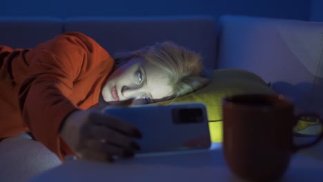 Young-Woman-saddened-by-a-phone-message-while-she-was-sleeping-at-night.