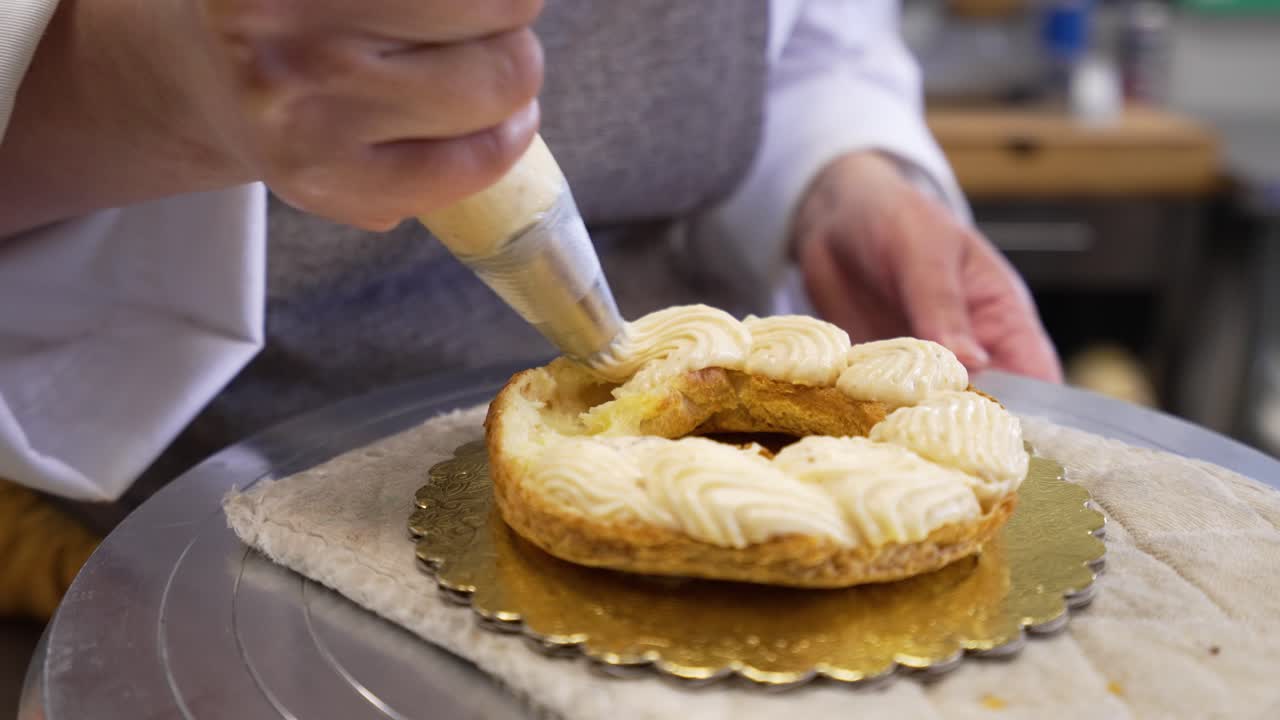Artisan baker uses piping bag to add creamy almond filling to buttery croissant shell, Chef filling round almond croissant, slow motion close up 4K
