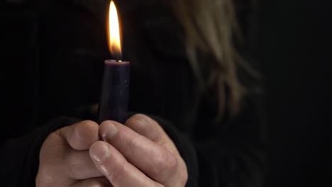 woman holding a long candle for vigil on dark background medium shot