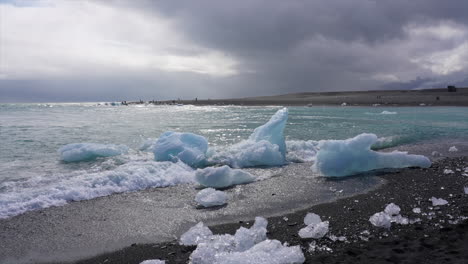 Wellen,-Die-Auf-Eisberge-An-Der-Küste-Des-Schwarzen-Strandes-In-Island-Krachen