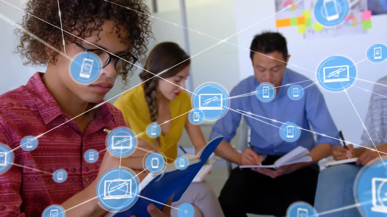 animación de una red de iconos digitales contra un hombre biracial tomando notas en la oficina.