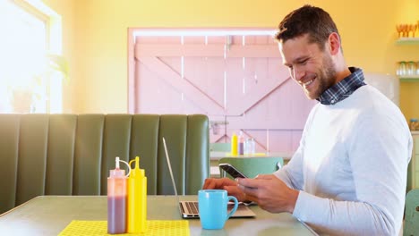 hombre chequeando su teléfono móvil mientras usa una computadora portátil 4k