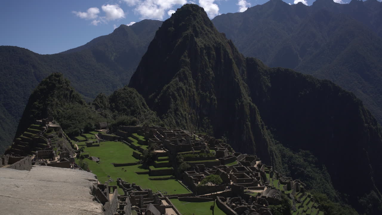 una impresionante vista panorámica de machu picchu, perú, muestra las majestuosas montañas de putu cusi y huayna, también se pueden ver los edificios que los antiguos incas construyeron con estructuras rectangulares.