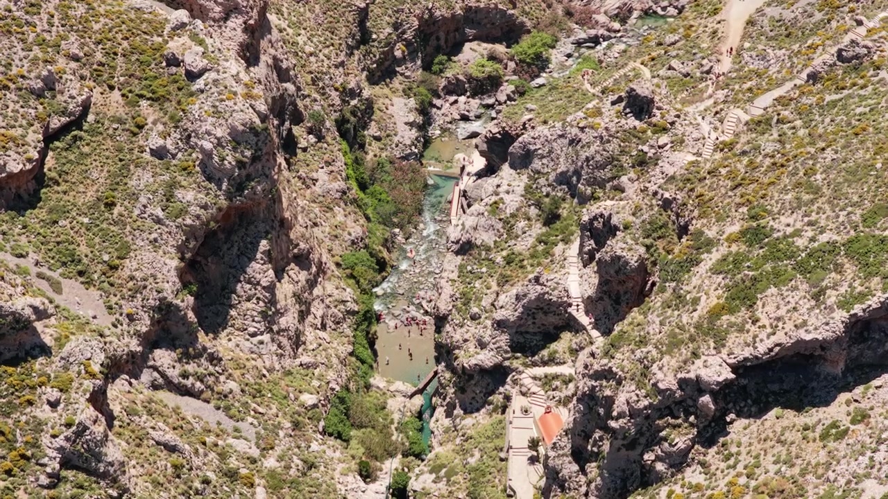 Vista aerea con drone di una gola fluviale rocciosa con pozze turchesi e persone che fanno il bagno tra i massi, Gola di Kourtaliotiko, Grecia