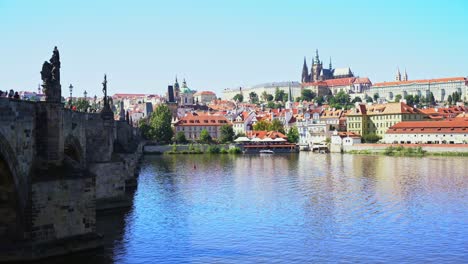 Puente-De-Carlos-Hacia-La-Pequeña-Ciudad-Donde-Se-Puede-Ver-El-Castillo-De-Praga-En-La-República-Checa,-Día-Soleado