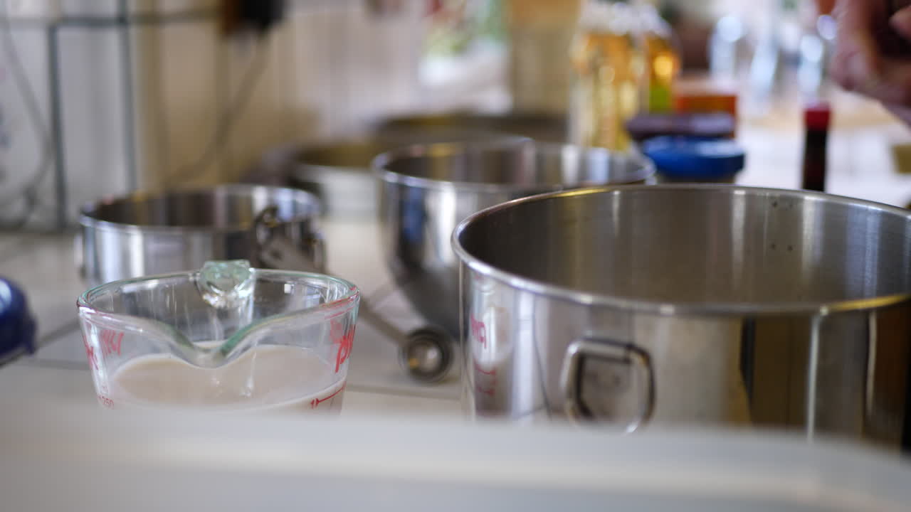 A woman chef measuring and scooping flour into a mixing bowl while baking a vegan chocolate cake for dessert in the kitchen