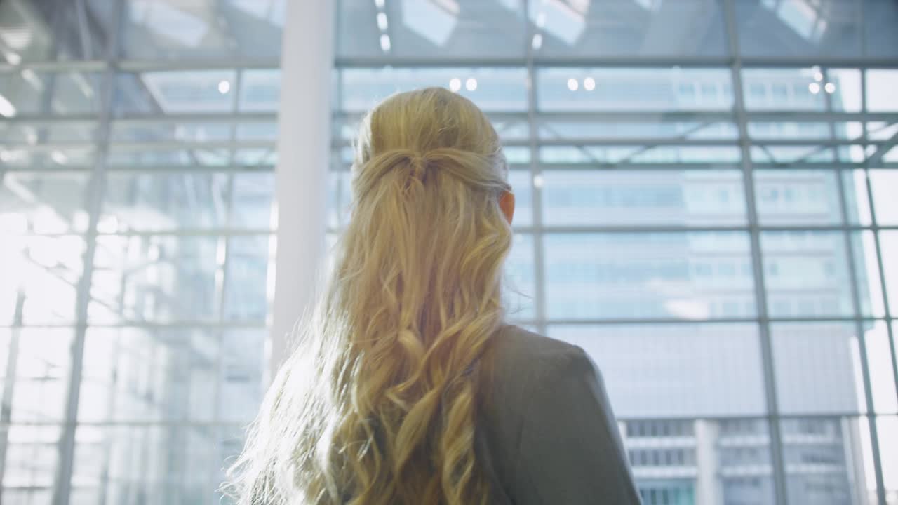 Woman pausing and looking up in glass atrium, icons growing around head showing social media buzz