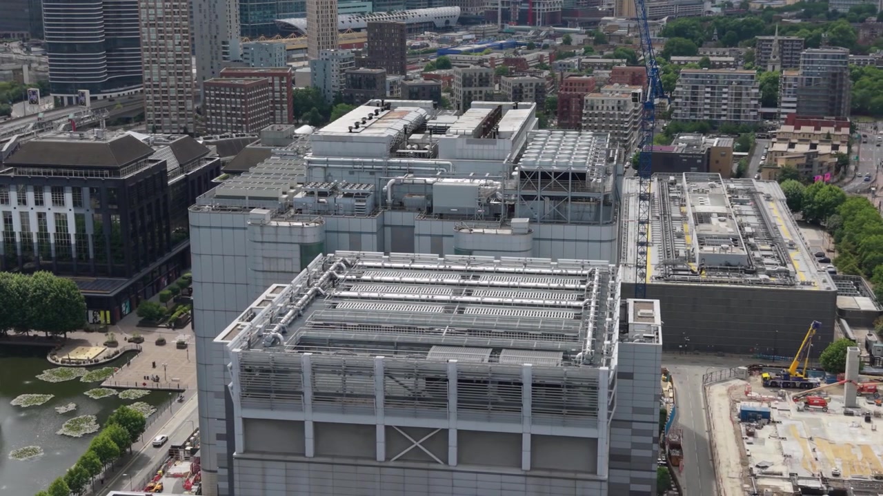 Prospettiva aerea di un grande complesso di Data Center in un'area metropolitana. Le vedute diurne mostrano vaste strutture edilizie e lavori di costruzione attivi accanto ad esse.