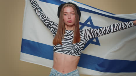 Mujer-Joven-En-Top-Corto-Ondeando-Y-Envolviendo-La-Bandera-Nacional-De-Israel,-Celebrando-El-Día-De-La-Independencia