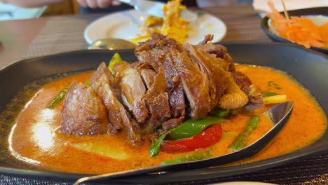 traditional crispy duck in spicy red curry sauce with vegetables, authentic thai cuisine restaurant, 4k shot