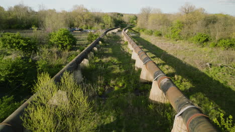 Vista-Elevada-De-Tuberías-Oxidadas-En-Un-Depósito-De-Chatarra-En-Fayetteville,-Arkansas,-Exuberante-Vegetación