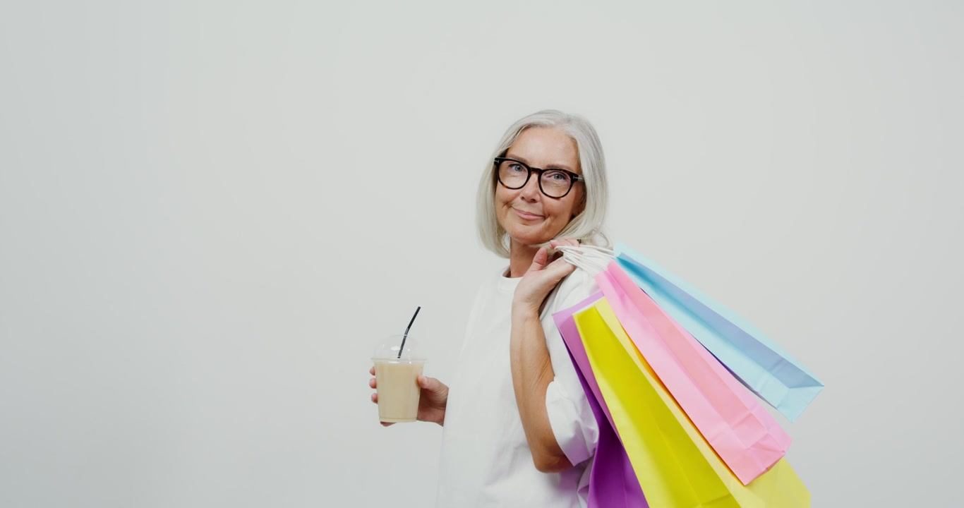 Donna anziana che fa shopping con un caffè da asporto