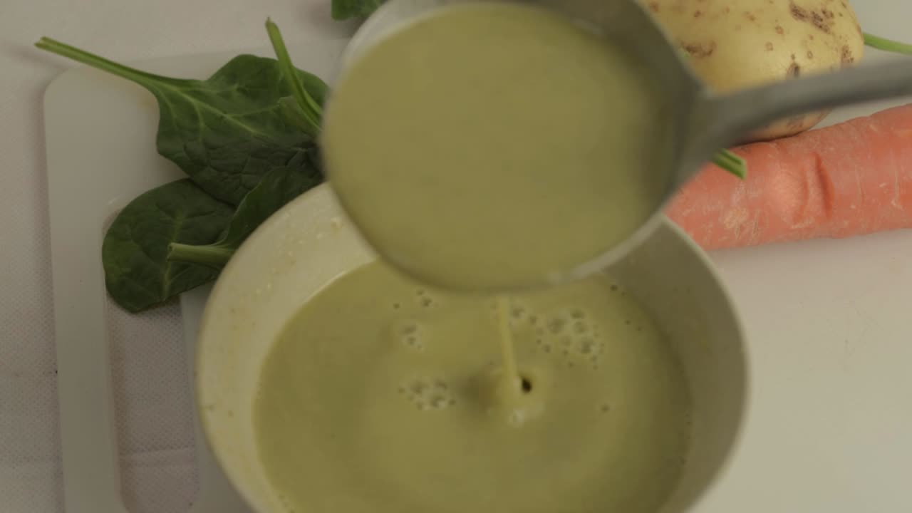 Pouring healthy vegetable soup into a bowl with ladle medium shot