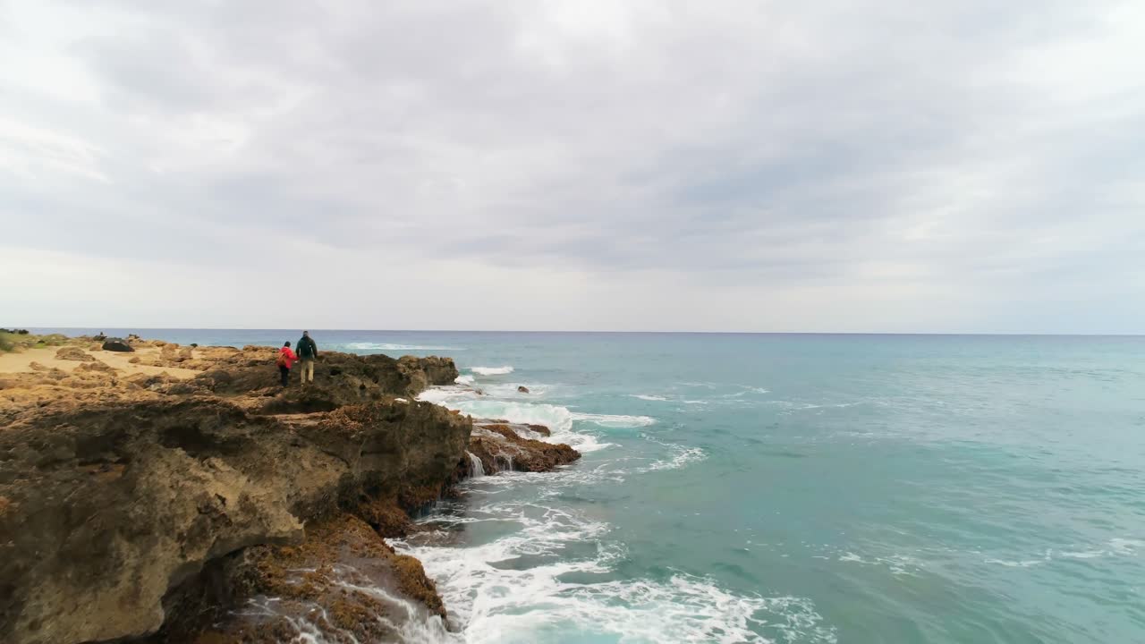 pareja caminando por la costa rocosa del mar 4k