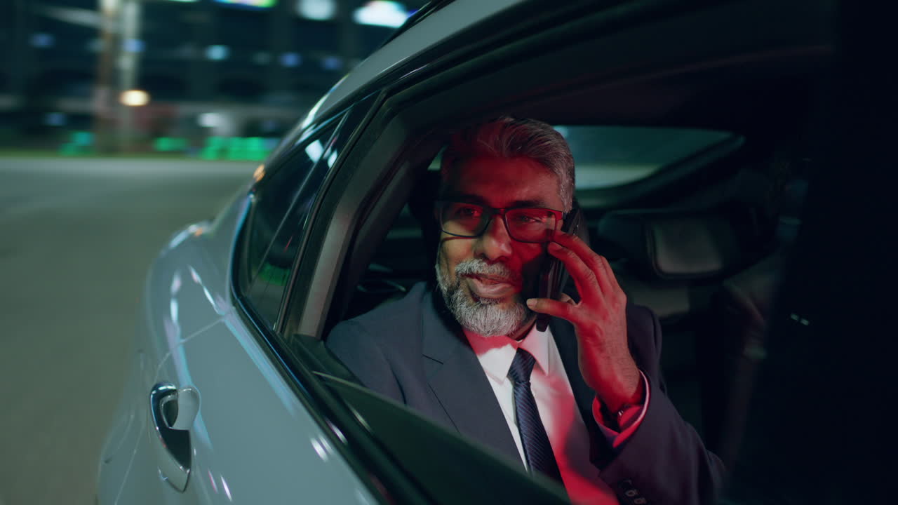 Businessman Speaking on Phone during Evening Car Ride through City