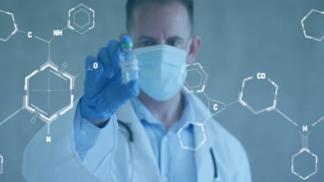 animation of chemical structures over caucasian male doctor holding vaccine wearing face mask