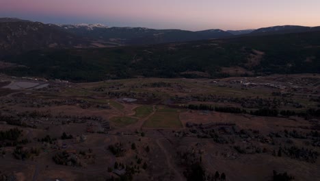 Drone-aerial-flyover-view-of-Big-Sky,-Montana-mountains-and-Golf-Course-at-dusk