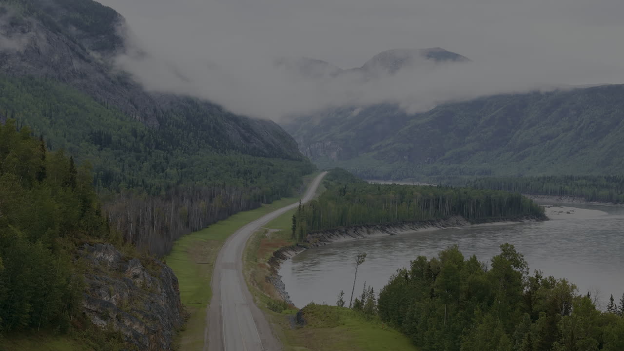 Fog-covered Alaska Highway cutting through rugged wilderness
