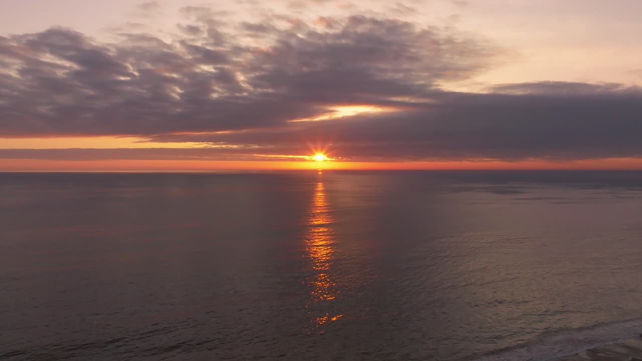 Aerial shot of the sun setting behind a large cloud off the coast of Chile