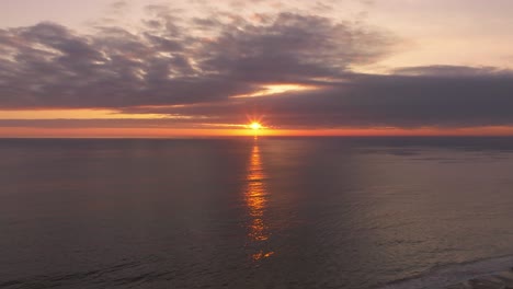 Aerial-shot-of-the-sun-setting-behind-a-large-cloud-off-the-coast-of-Chile