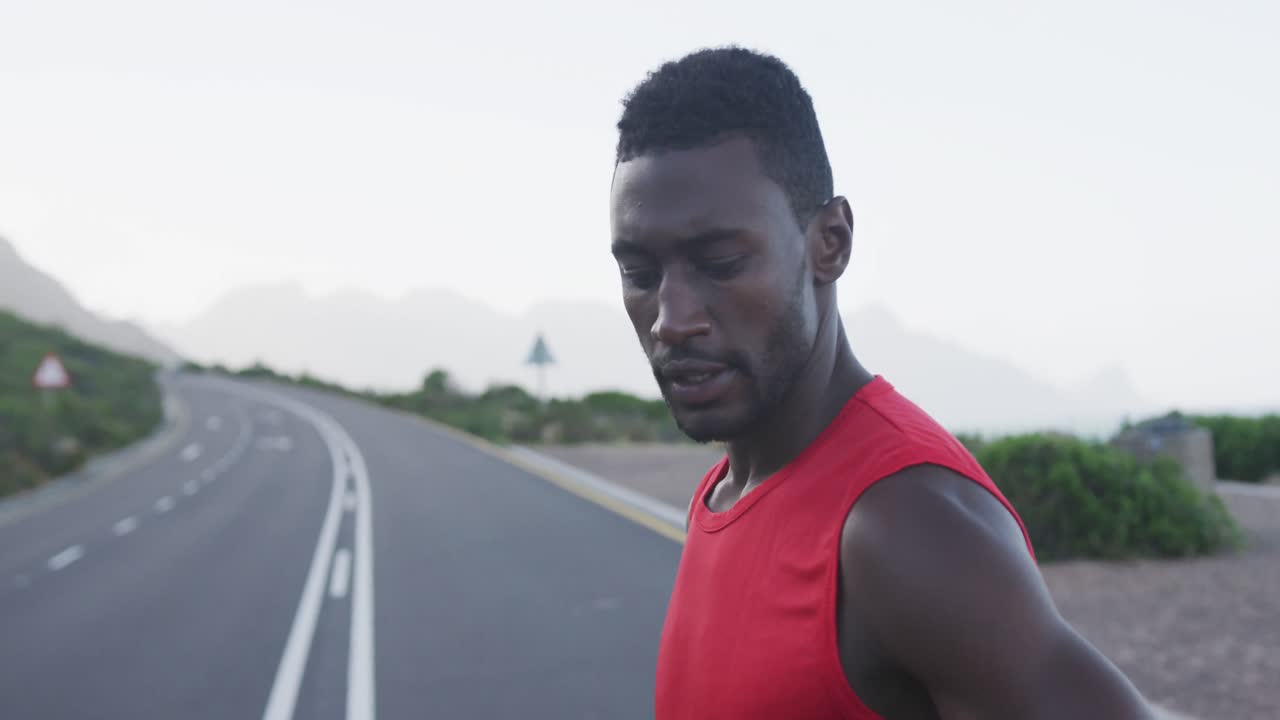 retrato de un hombre afroamericano haciendo ejercicio en un camino de montaña deteniéndose para descansar durante la carrera