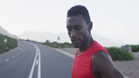 portrait of african american man exercising on mountain road stopping to rest during run