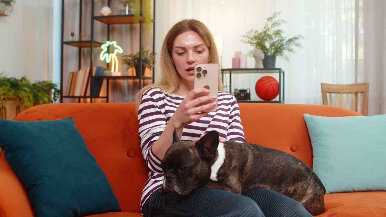 Middleaged woman with dog holds pet in arms and checks social media on smartphone calm morning mood