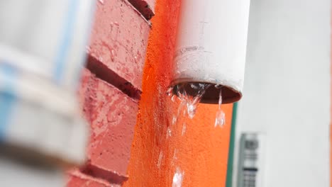 water dripping from gutter on orange house wall