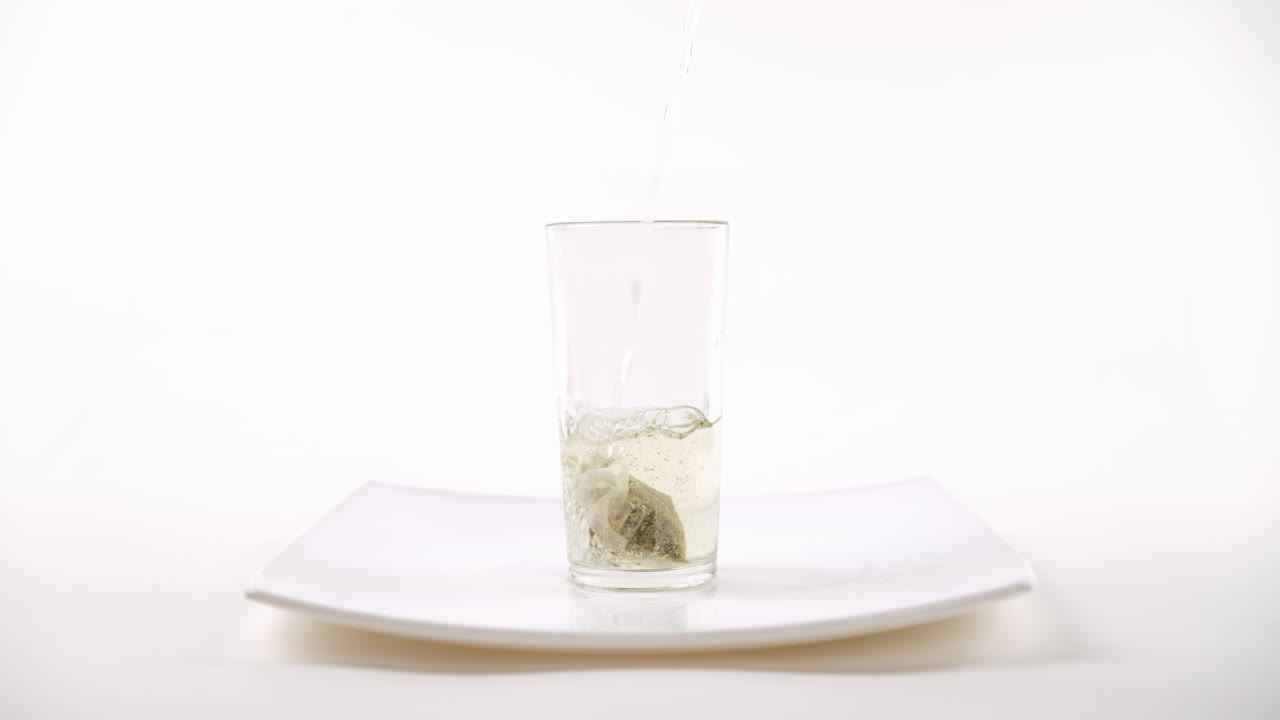 색 접시, 색 배경에 차 봉투와 함께 컵에 뜨거운 물을 부어 넣는 것