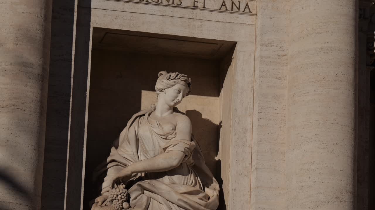 Close-up of the allegorical statue representing Abundance at the Trevi Fountain in Rome, Italy, holding a horn of plenty and bathed in warm sunlight.