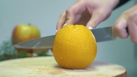 slow motion cutting big orange citrus fruit in two parts with a knife