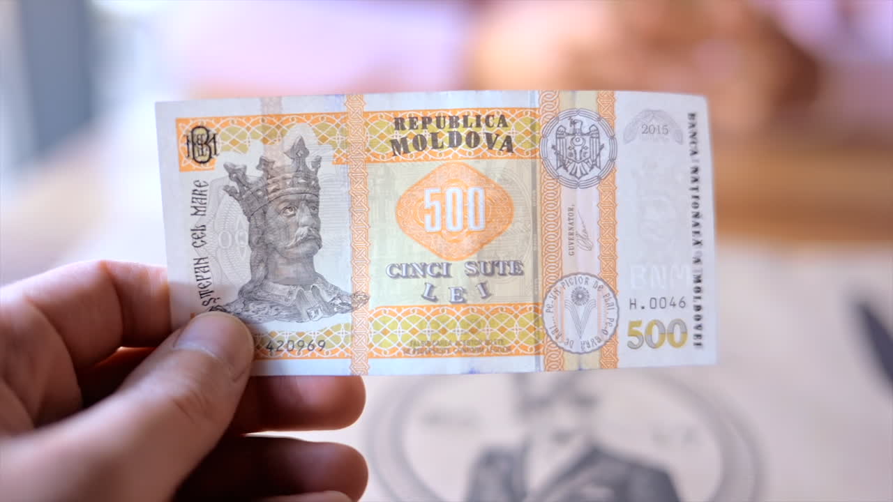 Close up of a man holding a 500 lei mdl bill
