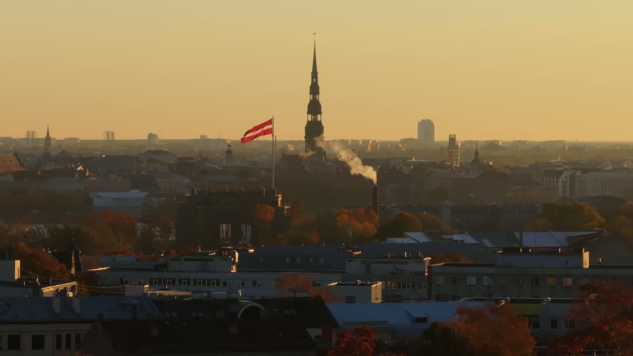 Tele drone shot at sunrise, showing Riga church, waving latvian flag - 4K.
