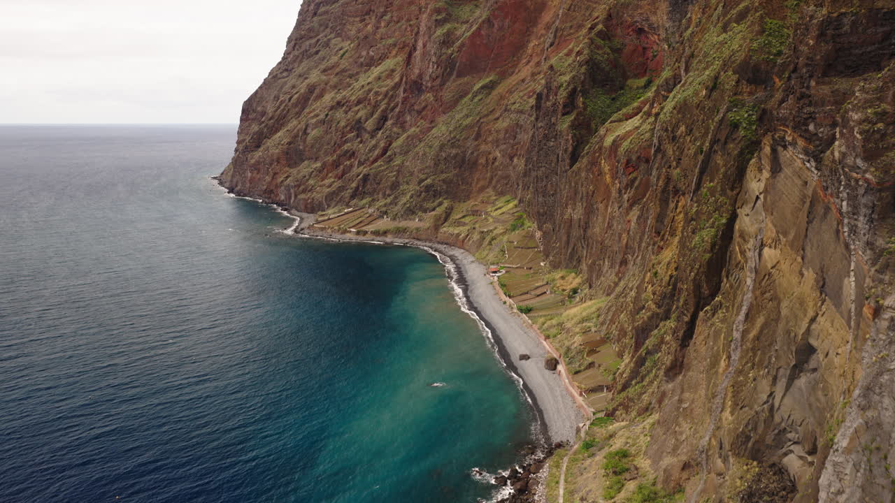 Vista Aérea da Costa Acidentada da Madeira com Falésias Íngremes e Oceano Azul.