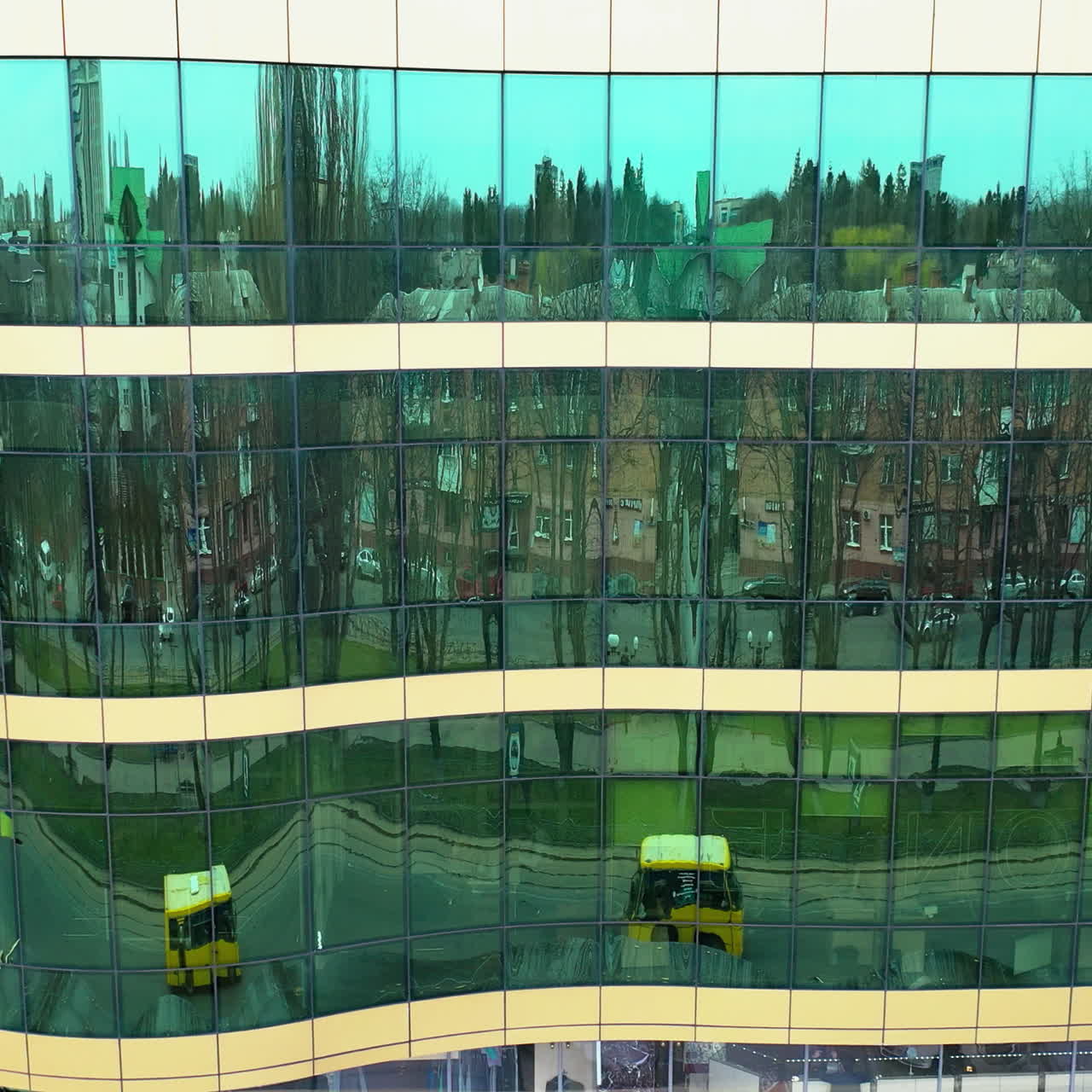 Cityscape reflection in the mirror windows of a modern architecture. Aerial shot of office building windows reflecting city outside. Camera moves right.