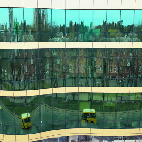 cityscape reflection in the mirror windows of a modern architecture. aerial shot of office building windows reflecting city outside. camera moves right.