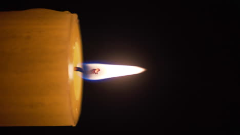 Candle-with-burning-flame-in-the-dark,-close-up