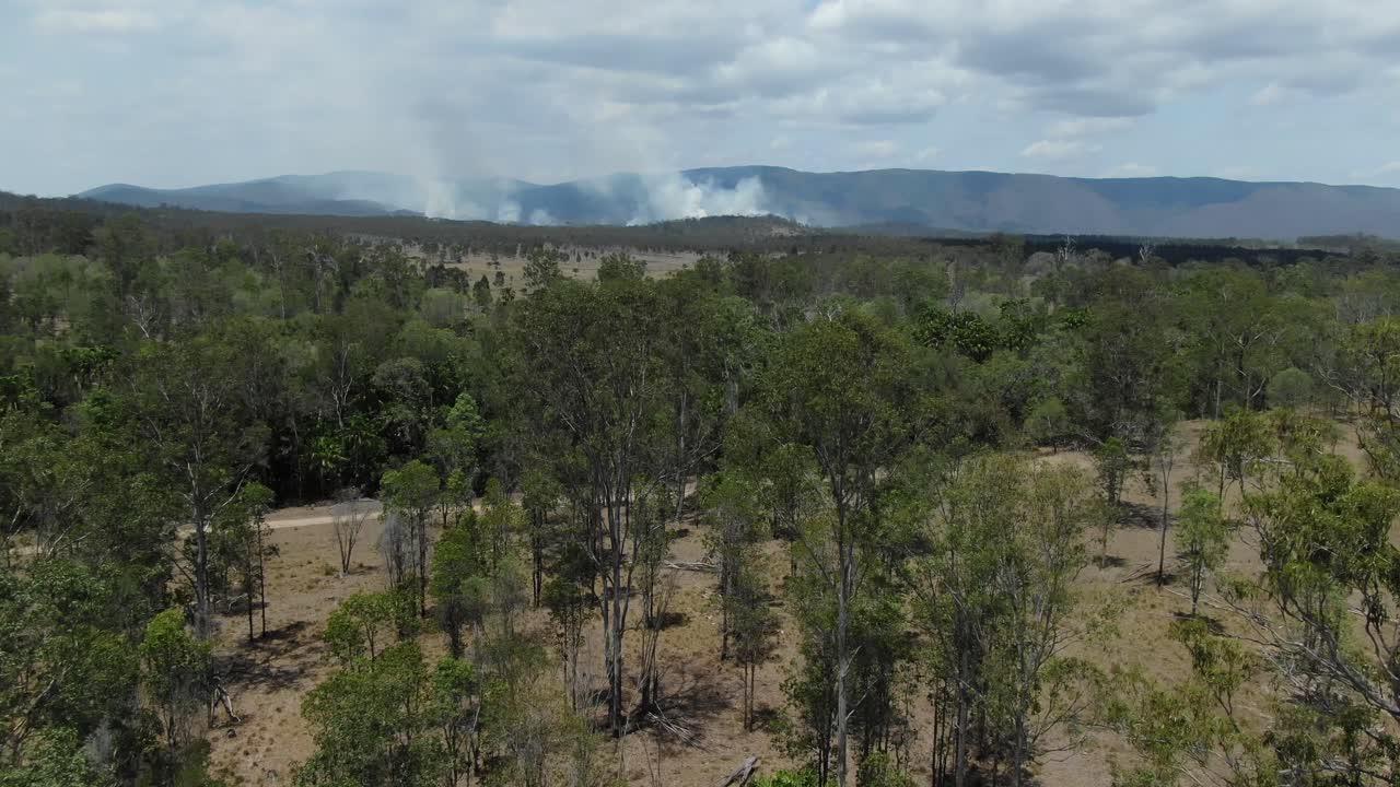 Deforestation fires and smoke over Queensland hills in Australia. Aerial drone forward pov