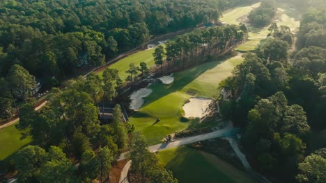 Magnífica-Vista-Aérea-De-Un-Campo-De-Golf-Durante-El-Amanecer-Mientras-El-Personal-De-Campo-Rueda-Los-Greens