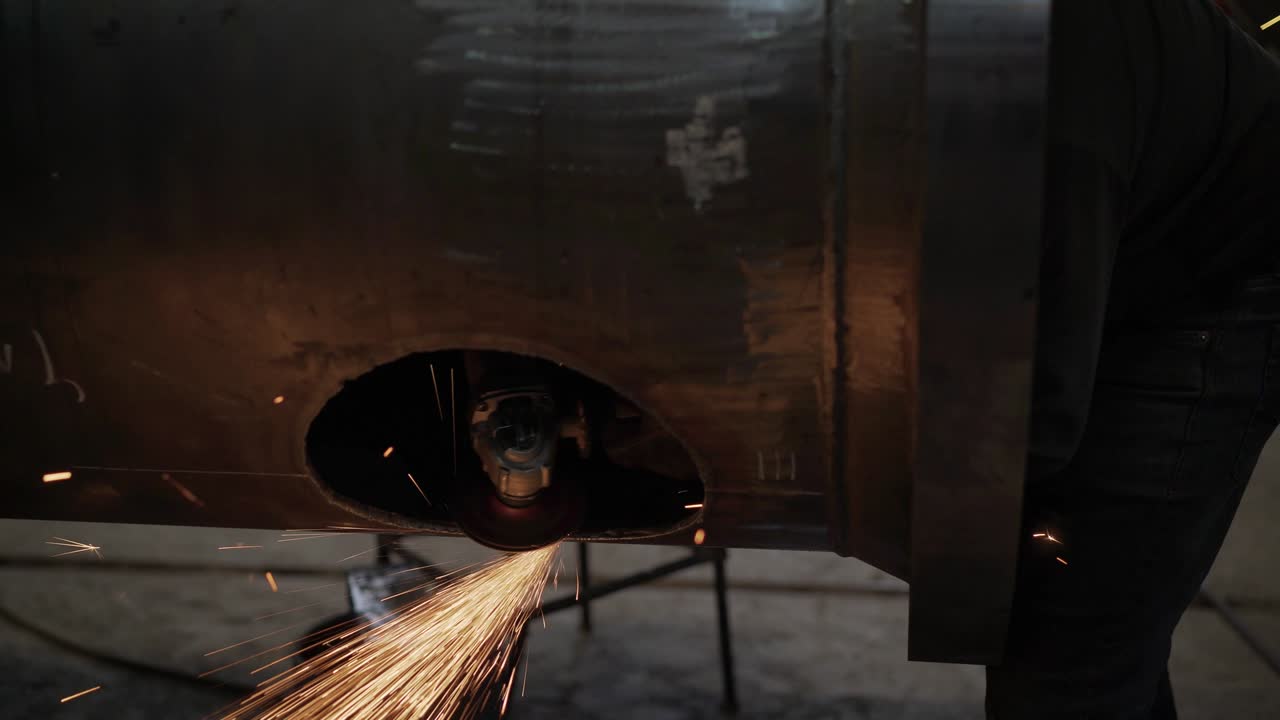 Heavy industry worker cuts a huge pipe. Work grinder cuts metal at the factory.