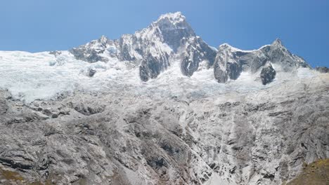 spectacular aerial tilt up shot from a turquoise glacial lagoon to the dramatic snow-capped taulliraju mountain peaks along the iconic santa cruz trek in peru’s cordillera blanca