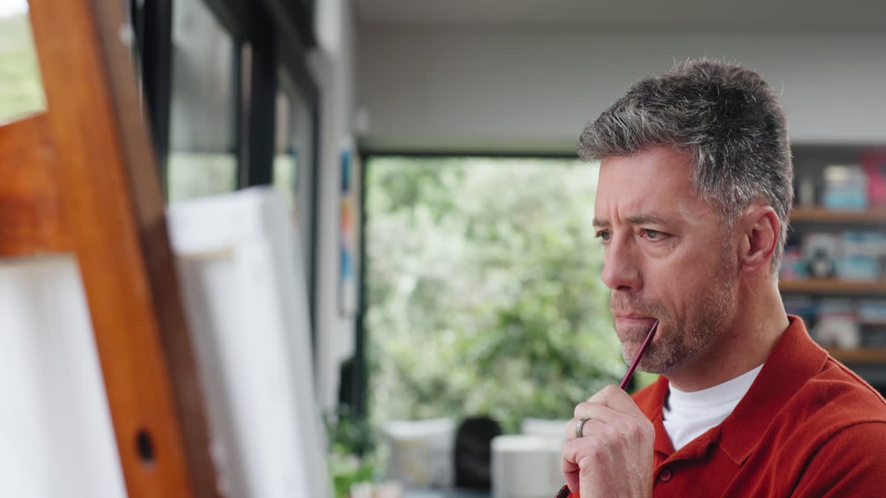 Focused Man Painting on Canvas with a Paintbrush at Home