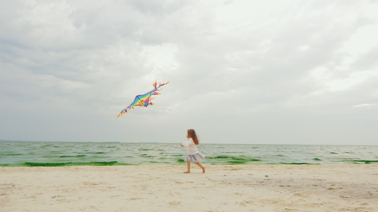 chica de 3 años jugando con una cometa en la playa 02
