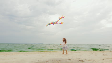 3yo girl playing with a kite on the beach 02