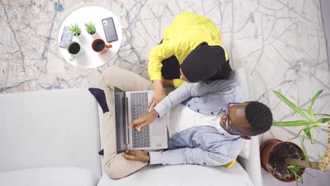 African-man-using-laptop-at-home-and-his-turbaned-wife-looking-after-him.