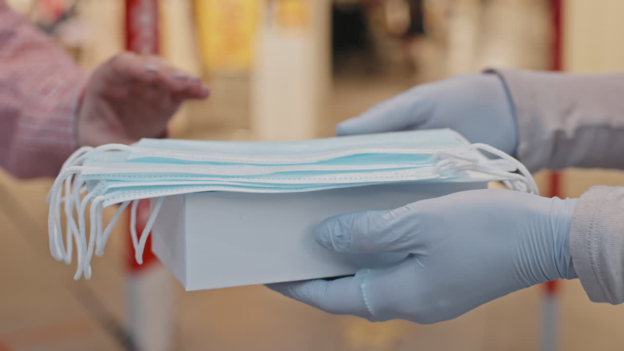 Close-Up Of Clothing Store Worker Giving Face Masks To Customers