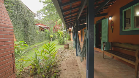 travelling shot of beautiful green garden with hammocks hanging on the porch at rustic villa