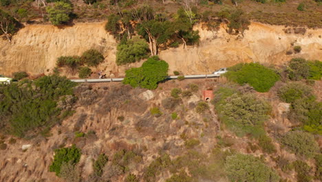 Vista-Aérea-De-Vehículos-Y-Ciclistas-Que-Viajan-A-Lo-Largo-De-La-Carretera-Victoria-En-Oudekraal,-Sudáfrica