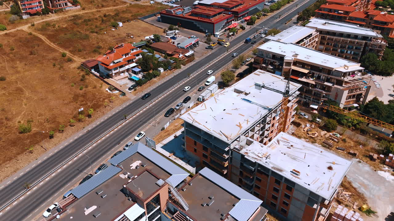 Varna, Bulgaria, 29 June 2025: Elevated scene of resort construction and coastal road. Unfinished structures stand beside finished properties in a dry summer landscape