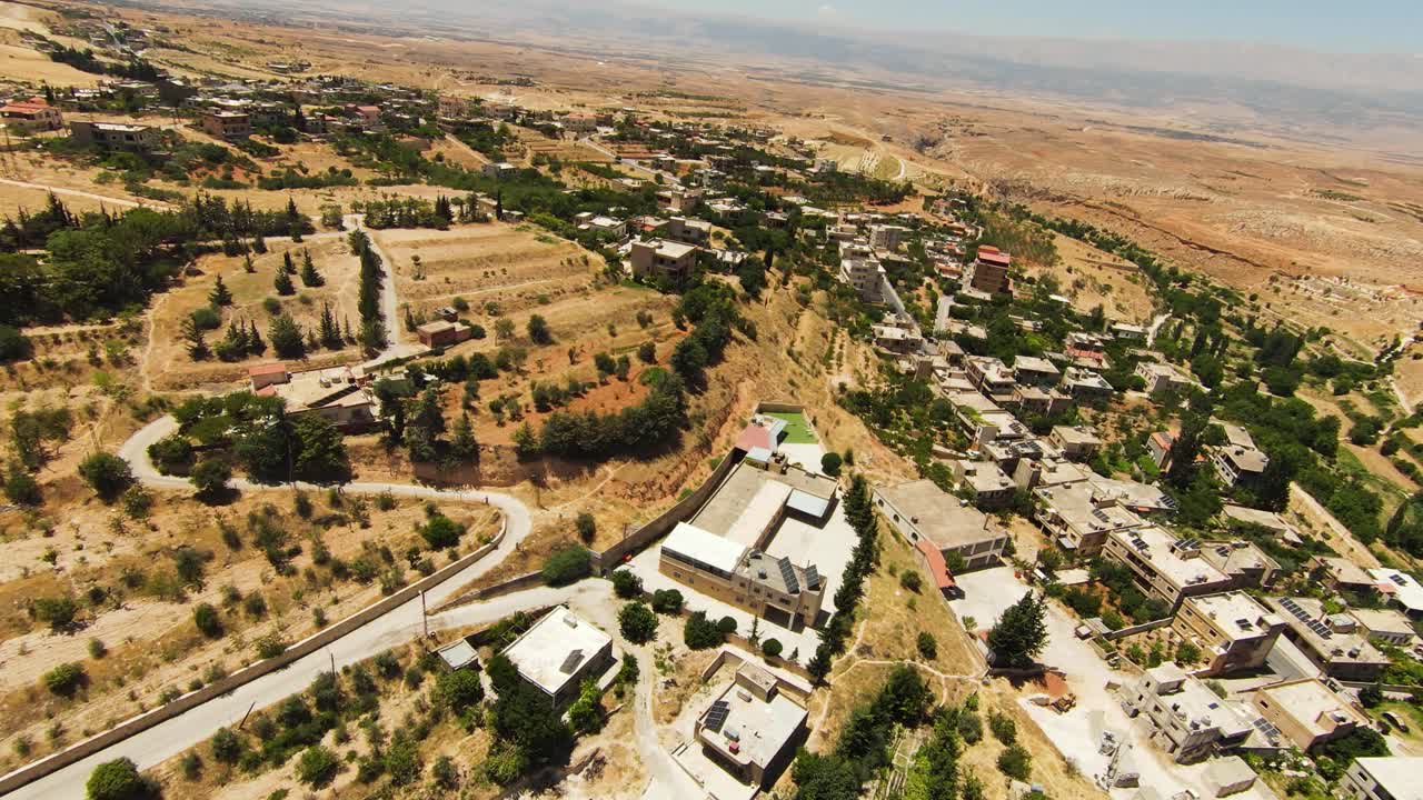 Aerial top down shot of sandy area of Lebanon with small village on hill during sunny day - panorama view